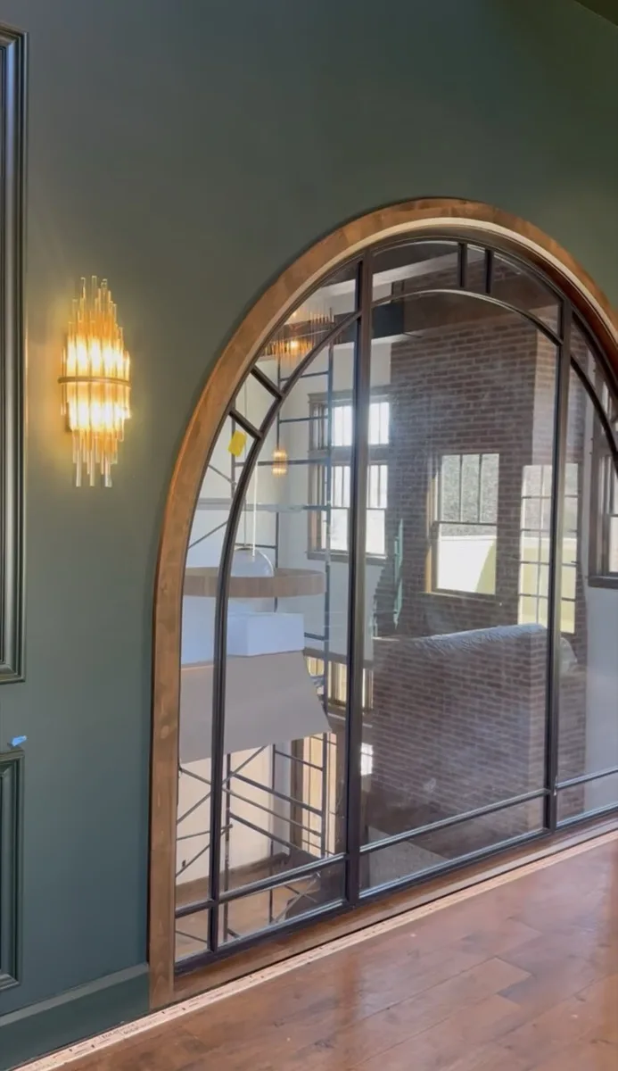 Arched mirror with tube sconce lighting in a home