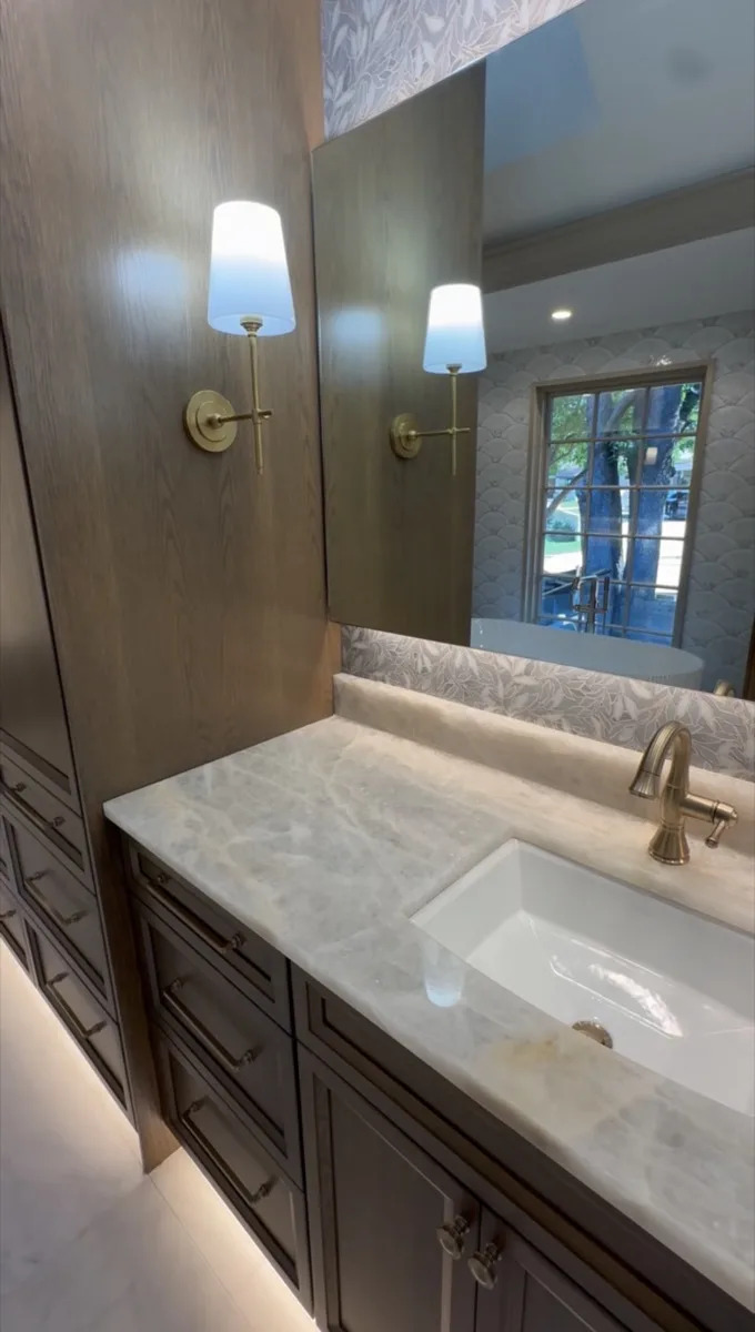 Bathroom vanity mirror with brass sconce lighting in a home