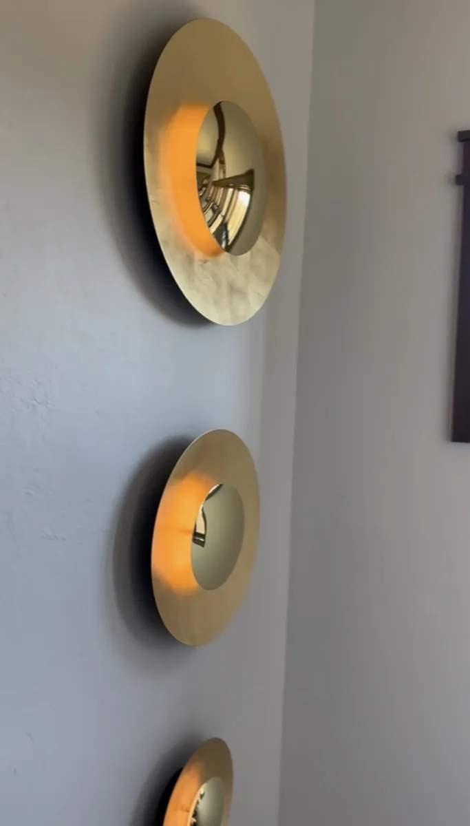 Brass convex disc sconce lighting detail in a home