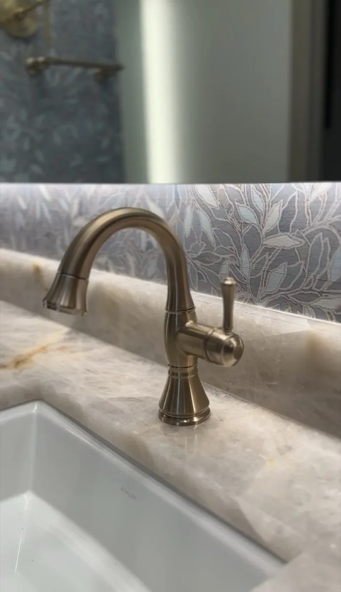 Brass faucet on a marble vanity counter in a bathroom
