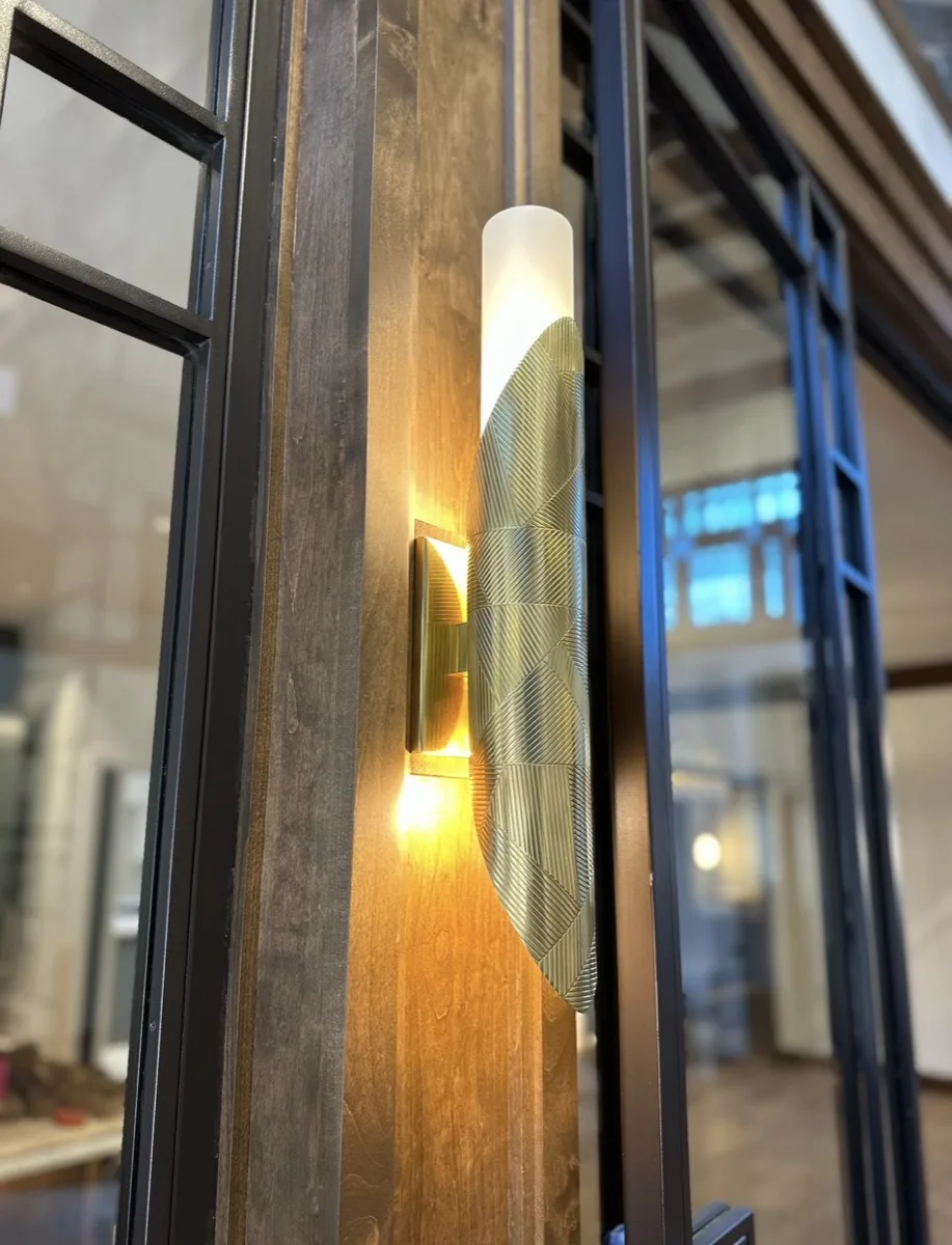 Brass leaf-textured sconce on a wood pillar in a home