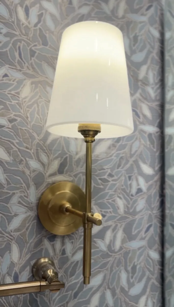 Brass wall sconce with glass shade in a bathroom