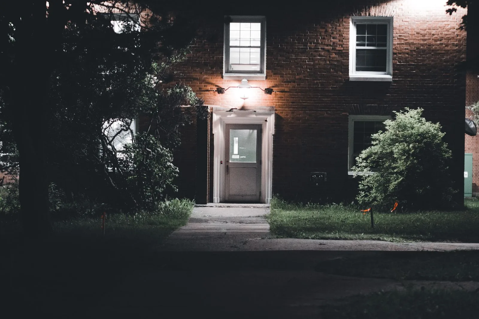 Brick home entrance lit by an exterior wall lantern at night