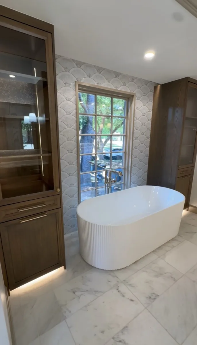 Freestanding tub with scalloped wallpaper in a primary bathroom