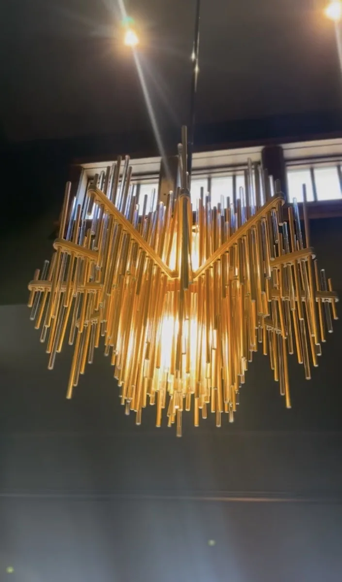 Gold rod sunburst pendant light near windows in a home
