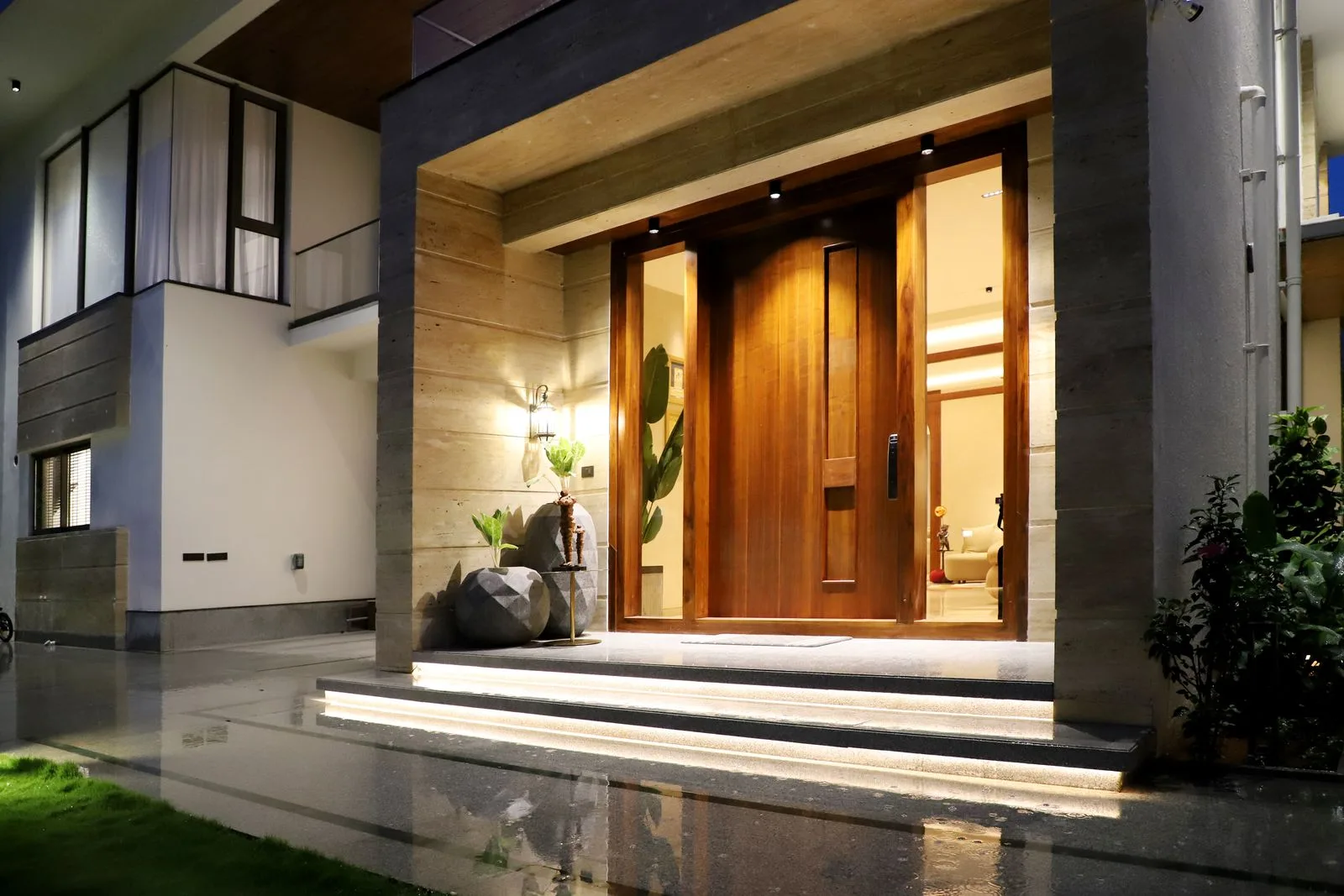 Modern home entry lit at night with an exterior wall lantern and illuminated entry steps