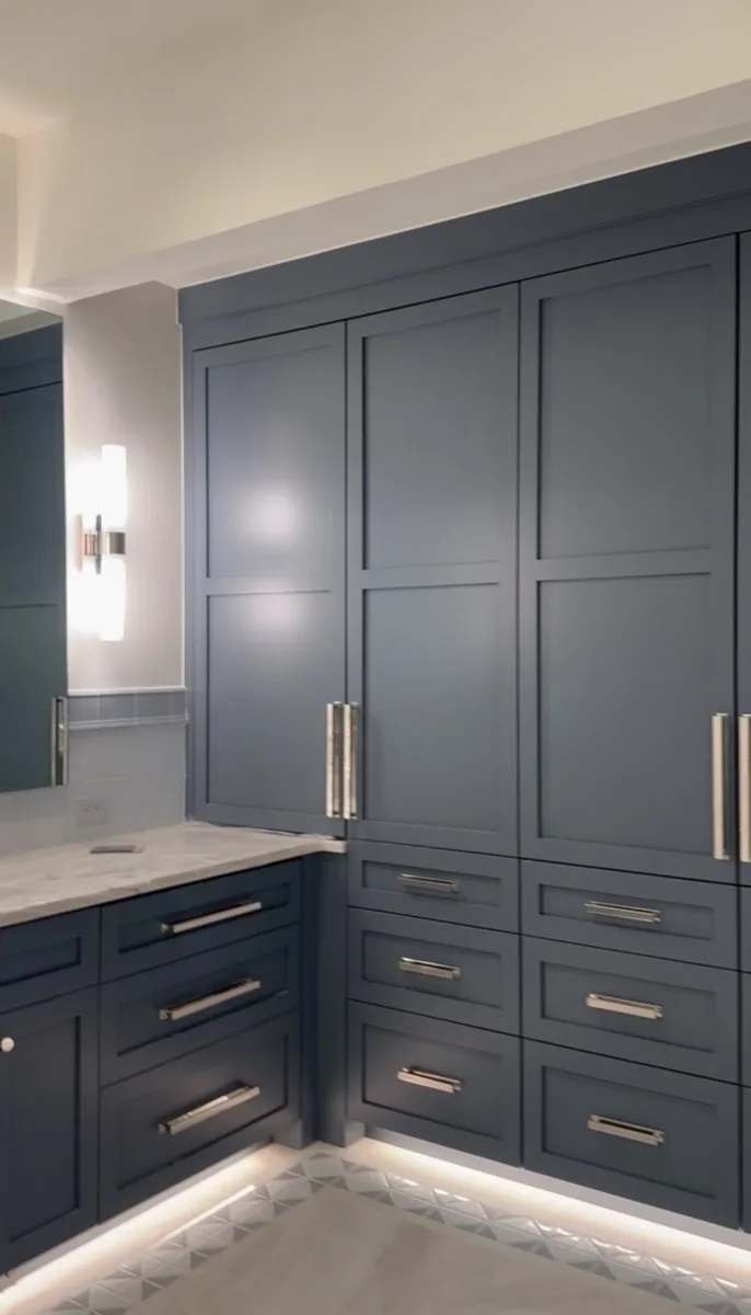 Cabinetry with chrome hardware and sconce lighting in a home