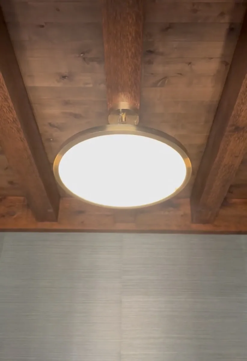 Round brass flush-mount ceiling light under wood beams in an OKC home